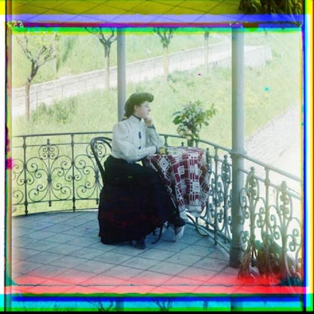 Женщина сидит на веранде с задумчивым видом.