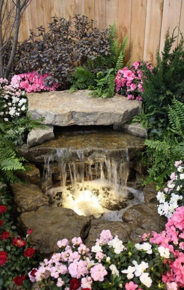 Маленький прудик с водопадом в окружении цветочной композиции
