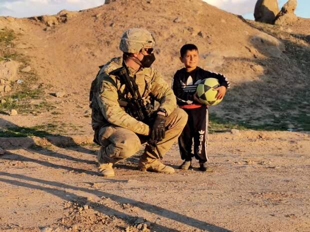 На фото: ребенок из деревни Хамза Баиг недалеко от сирийского города Рожава приветствует солдата США из Объединенной оперативной группы CJTF-OIR, в чьи обязанности также входит обеспечение безопасности близлежащих нефтяных месторождений.