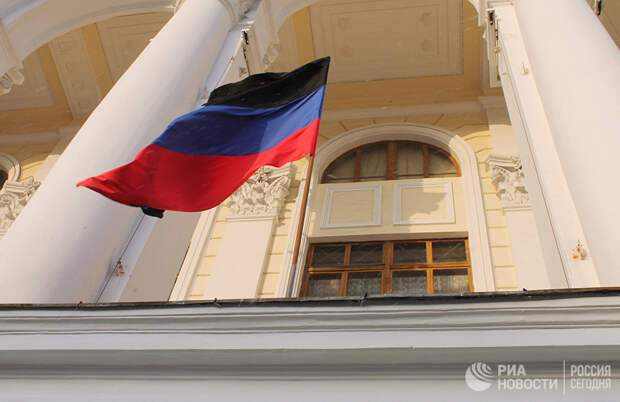 Флаг ДНР с траурной лентой на здании в Донецке