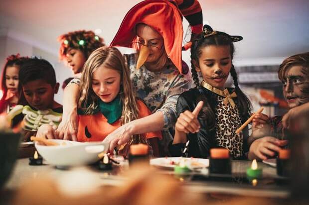 Adults and kids doing crafts at a halloween party