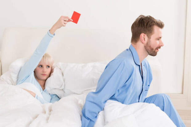 женщина показывает мужчине красную карточку в кровати