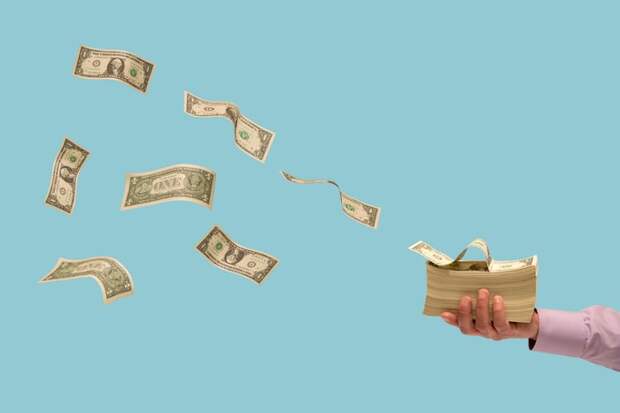Dollar bills flying off a stack of money.