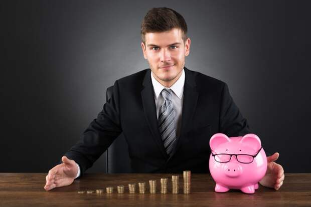 Businessman with piggy bank and coins stacked in piles