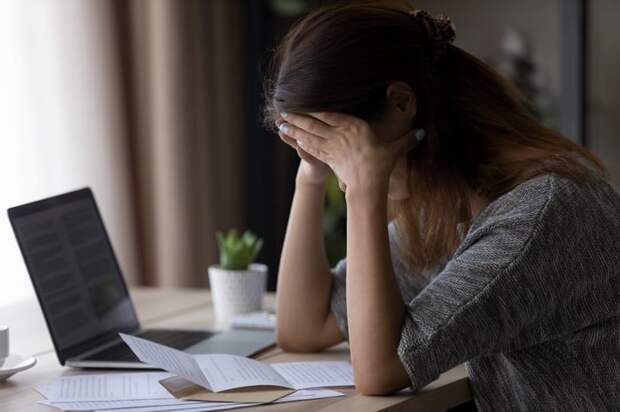 Woman appearing upset with head in her hands as she reads letter.