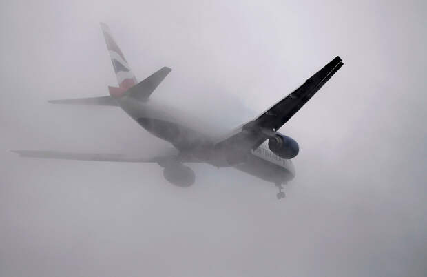 Самолет на посадке против тумана в аэропорту Хитроу в Лондоне