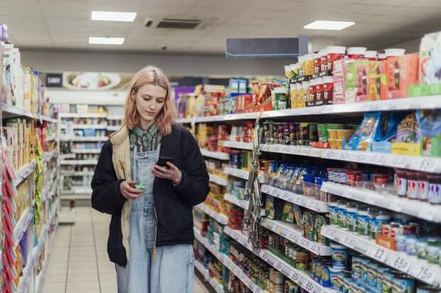 person shopping convenience store looking at phone