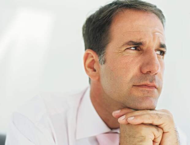 Person with hands under chin, staring off into the distance.
