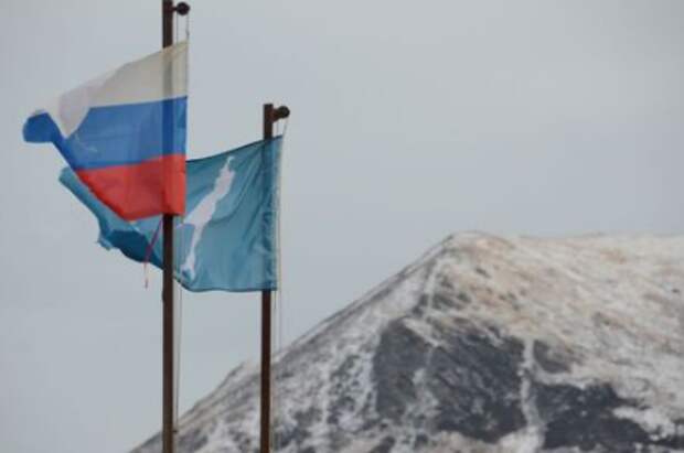 A national flag of Russia and a flag of Russia's Sakhalin region flutter in the village of Malokurilskoye on the island of Shikotan, Southern Kuriles, Russia, December 18, 2016. REUTERS/Yuri Maltsev