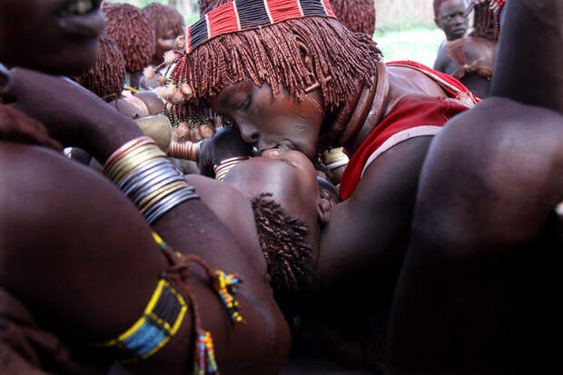 Женщина целует ребенка во время церемонии племени Хамер в долине Омо, Эфиопия вокруг света, путешествия, фотография