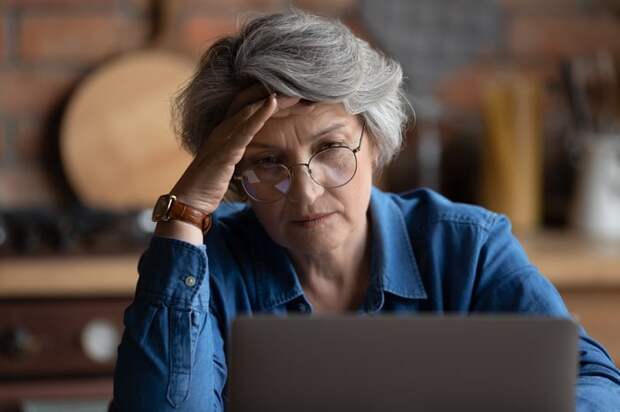 Woman looks at a laptop screen with a concerned expression on her face. 