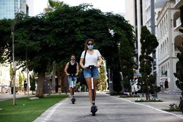 People wearing a protective face mask ride scooters ahead of a nationwide lockdown to contain the spread of the coronavirus disease (COVID-19), which is set to begin on Friday, in Tel Aviv, Israel September 15, 2020. REUTERS/Corinna Kern