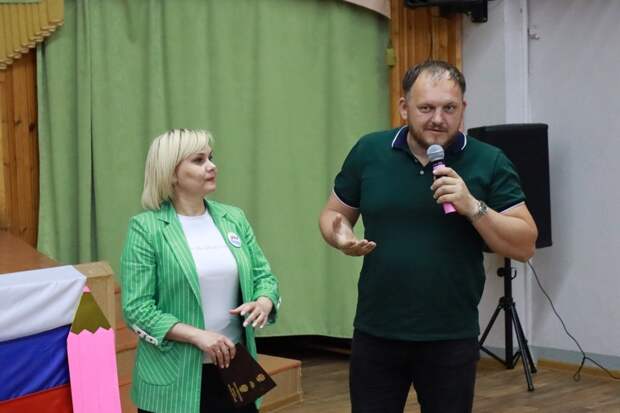 Мужчина и женщина ведут презентацию на сцене.