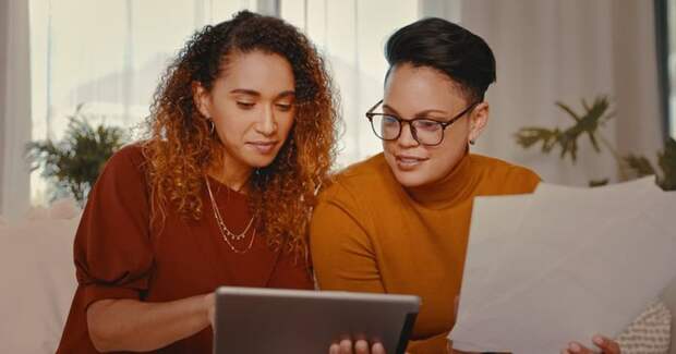 Two people at home looking at a tablet and paperwork.