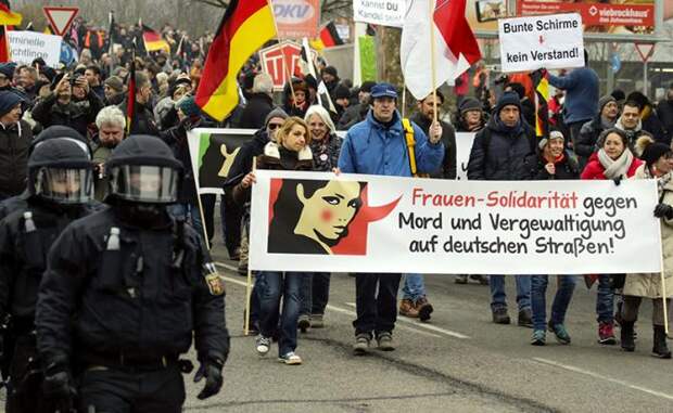 На фото: протестующие несут транспарант, на котором пишется: «Солидарны с женщинами - против убийства и изнасилования на немецких улицах!». Полицейские сопровождают марш. Кандель, Рейнланд-Пфальц, Германия, март 2018 года