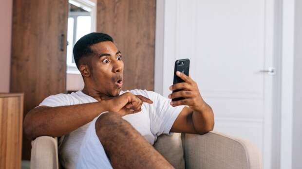 A man reacts surprisingly to something on his phone.