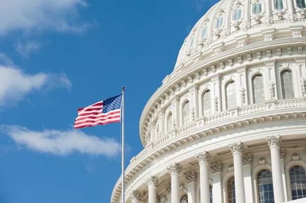 An American flag waving on a mast in front of the Capitol building in Washington. D.C.