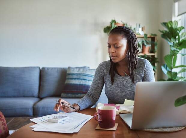 Woman making calculations as she uses her laptop.