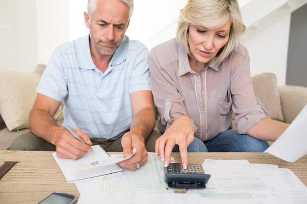 Two people looking at documents and a calculator.