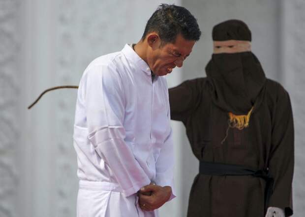Jono Simbolon (front), an Indonesian Christian, grimaces in pain as he is flogged in front of a crowd outside a mosque in Banda Aceh, Aceh province, on January 19, 2018. Simbolon was publicly flogged on January 19 for selling alcohol in conservative Aceh province, a violation of Islamic law, as a crowd of onlookers including children jeered