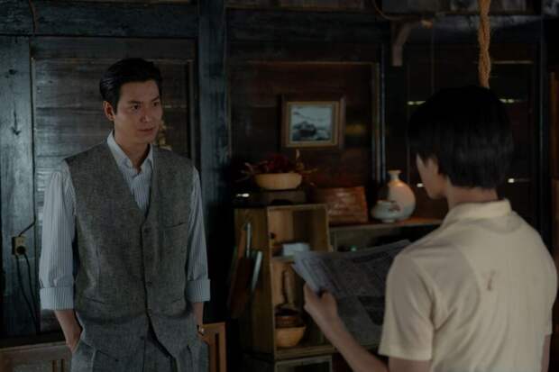 Koh in sweater vest and Noa in yellow shirt stand inside the barn