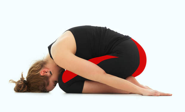 young woman in relaxing yoga pose, dressed in black on white background