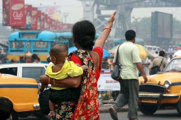 Мама с маленьким ребенком на руках пытается перейти улицу возле станции Хавра.