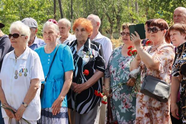 Пожилые люди на мероприятии с гвоздиками и медалями