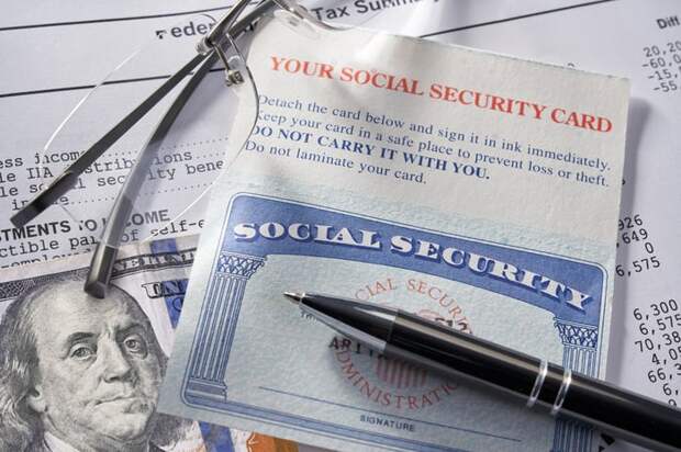 A Social Security card, on top of financial statements and a $100 bill. A pen and glasses laying on top.