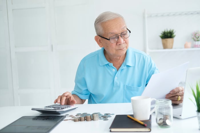 A person holding a document and using a calculator.