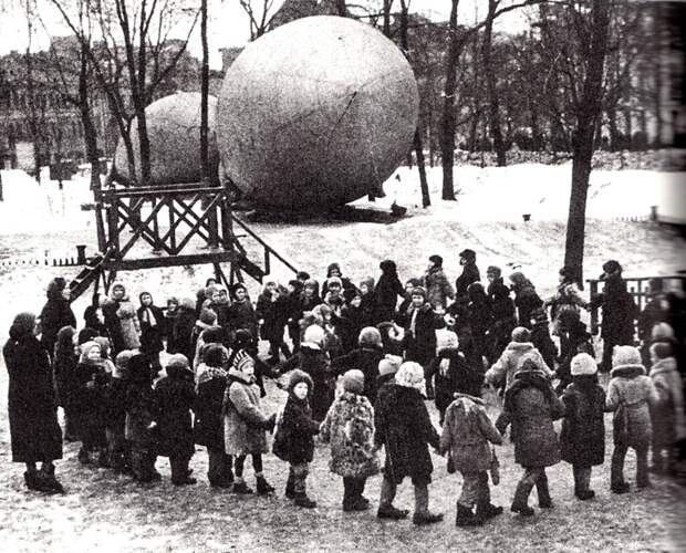 Дети водят хоровод на фоне аэростатов воздушного заграждения. Скорее всего — начало зимы 1941 года.  Москва. 