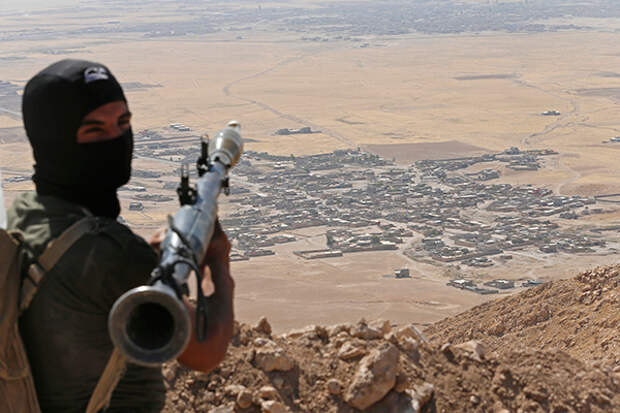 A Kurdish Peshmerga fighter holds a a rocket-propelled grenade launcher as he takes up position in an area overlooking Baretle village (background), which is controlled by the Islamic State, in Khazir, on the edge of Mosul September 8, 2014.