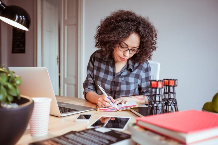 Woman taking notes while using a laptop