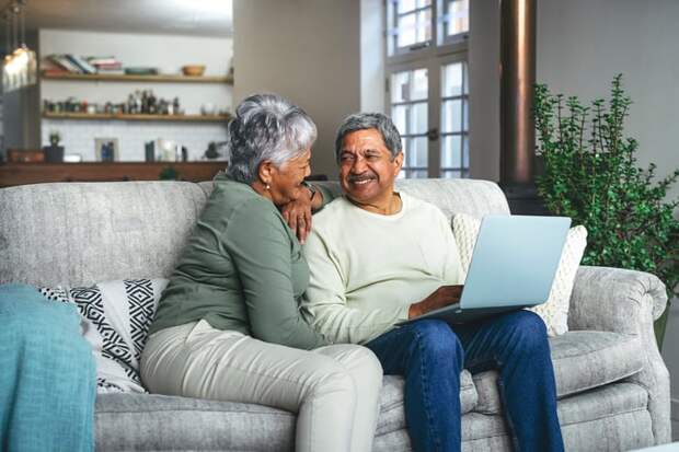 Two people sitting on a couch and using a laptop.
