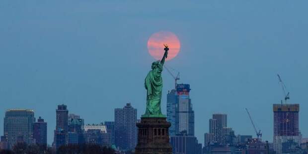 The last supermoon of 2019 rises behind the Statue of Liberty in New York, United States on March 20, 2019.