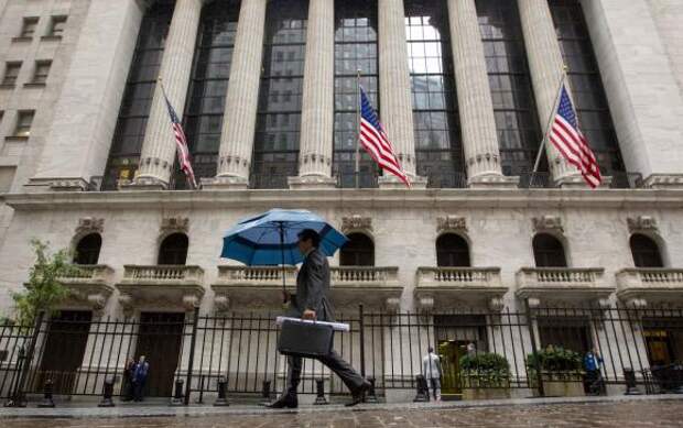 A man carries an umbrella in the rain as he passes the New York Stock Exchange October 16, 2014.  REUTERS/Brendan McDermid