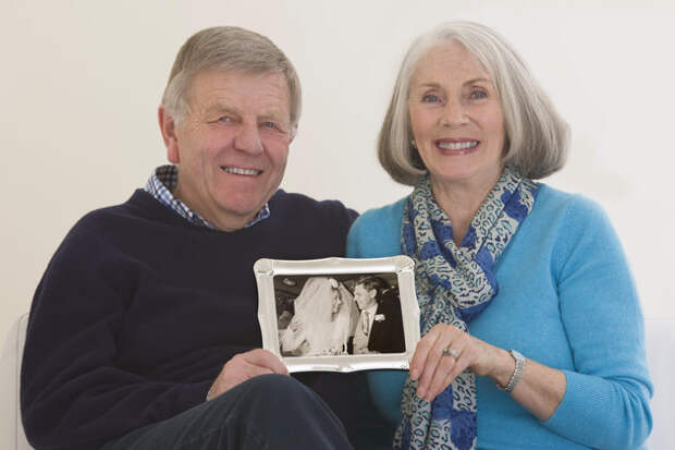 senior couple holding a framed wedding photogh