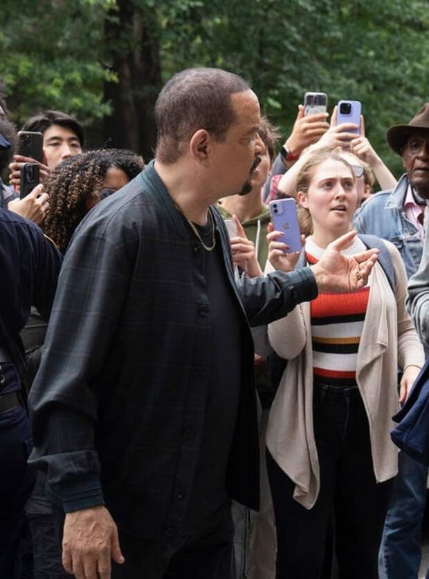 Fin holds out a hand in exasperation while surrounded by a crowd of young people filming a police encounter on Law & Order: SVU Season 26 Episode 1