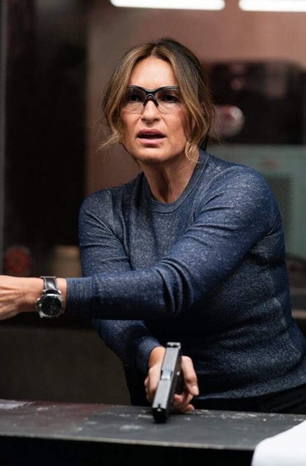 Benson at the shooting range wearing safety googles and holding a gun in her right hand pointed toward a table on Law & Order: SVU Season 26 Episode 1