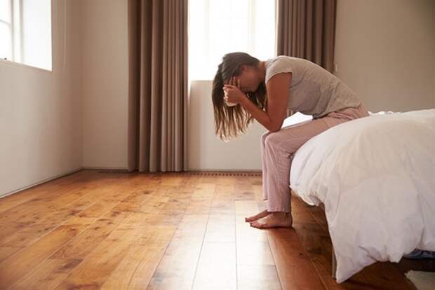 Woman Suffering From Depression Sitting On Bed And Crying