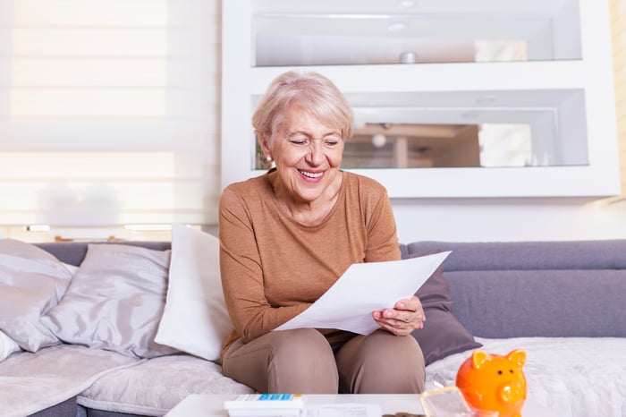 A seated smiling person holding a document.