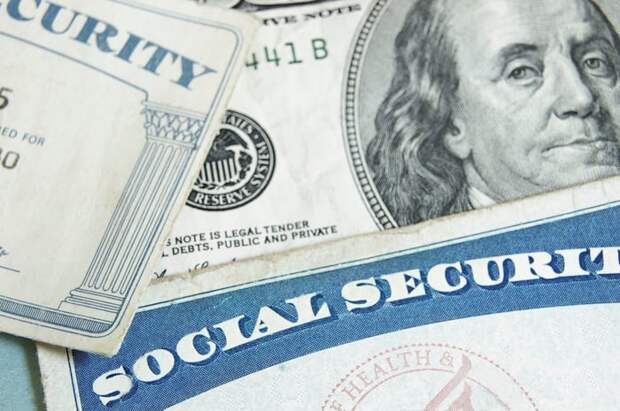 Two Social Security cards laid atop a $100 bill.