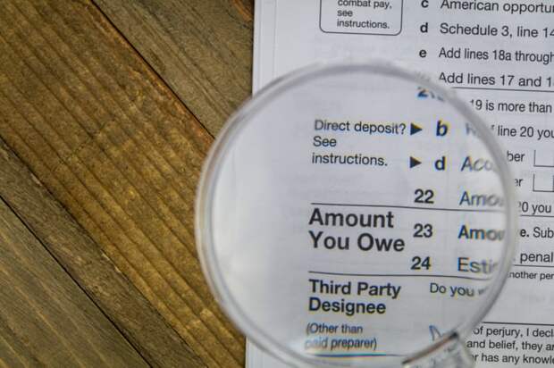 A magnifying glass held above an IRS tax form that's enlarged the phrase, Amount You Owe.