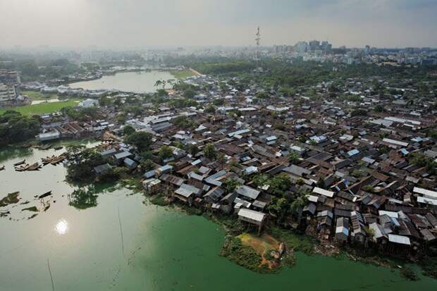 Переломный момент.  Трущобы Дакки, такие как Кораил (на заднем плане) переполненные беженцами, являются огромной проблемой для города, который страдает от устаревшей инфраструктуры, высокого уровня бедности и постоянных паводков.