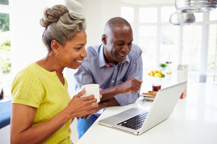 Smiling couple looking at laptop together.