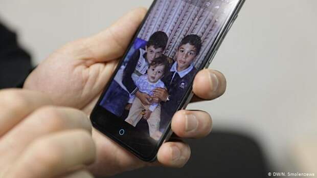 Хасан показывает фотографию своих детей 