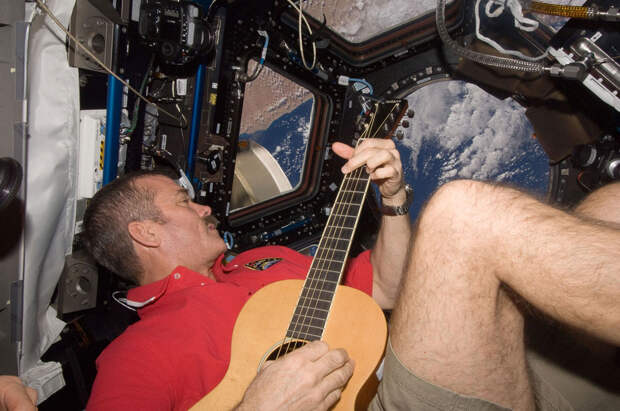 Астронавт Канадского космического агентства Крис Хэдфилд с гитарой на фоне видов Земли