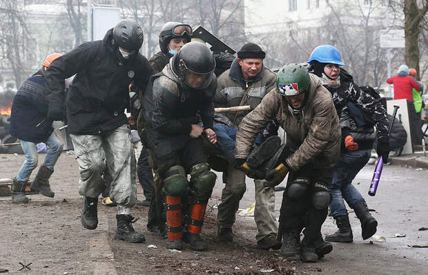 Протестующие переносят раненого во время беспорядков в Киеве, 20 февраля 2014 года
