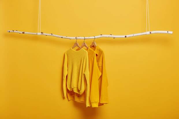 selective-focus-three-items-clothes-hangers-long-sleeved-yellow-jumpers-wooden-rack-near-bright-vivid-wall-1024x683 Как  одеваться стильно в одном цвете: 6 правил монохромных образов