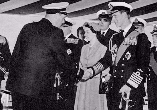 Елизавета II и её муж Филипп, приветствуют морского офицера Рудакова.